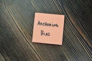 Concept of Anchoring Bias write on sticky notes isolated on Wooden Table. photo