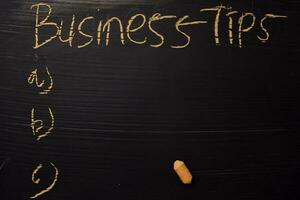 Business Tips written with color chalk. Supported by an additional services. Blackboard concept photo