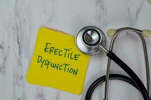 Erectile Dysfunction write on sticky notes isolated on Wooden Table. photo