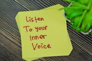 Concept of Listen To Your Inner Voice write on sticky notes isolated on Wooden Table. photo