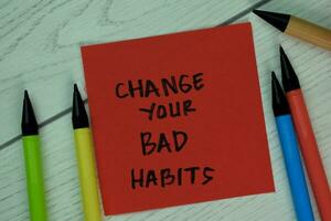 cambio tu malo hábitos escribir en pegajoso notas aislado en de madera mesa. foto