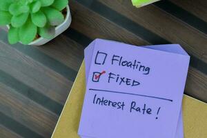 Concept of Someone choose fixed interest rate write on a sticky notes isolated on Wooden Table. photo