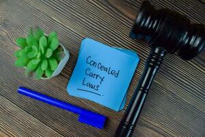 Concealed Carry Laws write on sticky notes isolated on Wooden Table. photo
