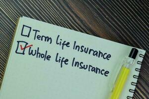 Concept of Whole Life Insurance write on a book isolated on Wooden Table. photo