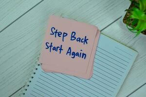 Concept of Step Back Start Again write on sticky notes isolated on Wooden Table. photo