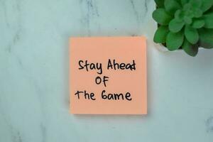 Concept of Stay Ahead Of The Game write on sticky notes isolated on Wooden Table. photo