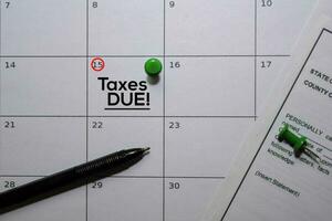 Taxes DUE text on white calendar background. Reminder or schedule concept photo