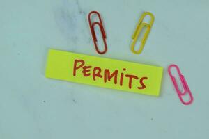 Concept of Permits write on sticky notes isolated on Wooden Table. photo