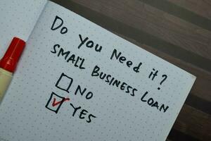 Small Business Loan write on a book and supported by additional services isolated on Wooden Table. photo