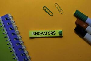 Innovators write on sticky notes. Isolated on orange table background photo
