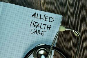 Allied Health Care write on a book isolated on Wooden Table. photo