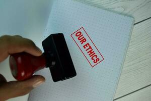 Red Handle Rubber Stamper and Our Ethics text isolated on the table. photo