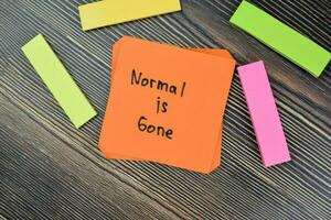 Concept of Normal Is Gone uncertainty during coronavirus pandemic write on sticky notes isolated on Wooden Table. photo