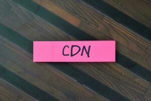 Concept of CDN - Content Delivery Network write on sticky notes isolated on Wooden Table. photo