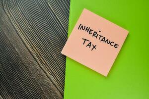 Concept of Inheritance Tax write on sticky notes isolated on Wooden Table. photo