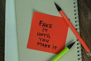 Fake it Until You Make it write on sticky notes isolated on Wooden Table. photo