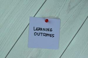 Concept of Learning Outcomes write on sticky notes isolated on Wooden Table. photo