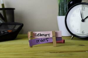 Customers and Orders. Handwriting on sticky notes in clothes pegs on wooden office desk photo