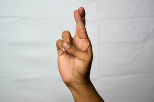 Close up Asian man shows hand gestures it means Fingers Crossed isolated on white background photo