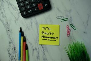 Total Quality Management write on sticky notes isolated on office desk. photo