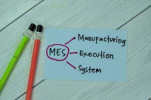 Concept of MES - Manufacturing Execution System write on sticky notes isolated on Wooden Table. photo