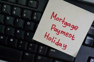 Mortgage Payment Holiday write on sticky notes isolated on Wooden Table. photo