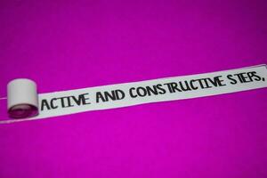 Active and Constructive Steps text, Inspiration and positive vibes concept on purple torn paper photo