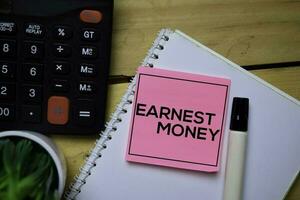 Earnest Money write on sticky note with wooden table background photo