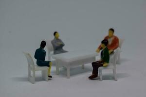 Close up model toy or miniature couple sitting on the chair and two male talking a business photo