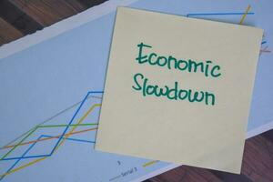 Economic Slowdown write on sticky notes isolated on Wooden Table. photo