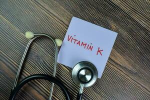 Concept of Vitamin K write on sticky notes isolated on Wooden Table. photo