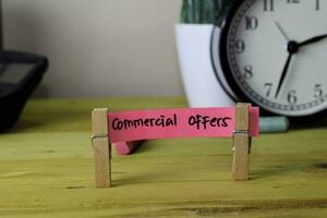 Commercial Offers. Handwriting on sticky notes in clothes pegs on wooden office desk photo