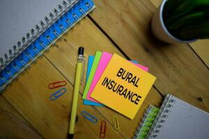 Bural Insurance write on a sticky note isolated on wooden background. photo