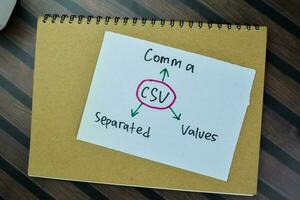 Concept of CSV - Comma Separated Values write on sticky notes isolated on Wooden Table. photo