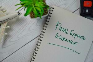 Final Expense Insurance write on a book isolated on Wooden Table. photo