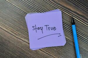 Concept of Stay true write on sticky notes isolated on Wooden Table. photo