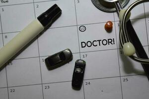 Doctor text on white calendar background. Reminder or schedule concept photo