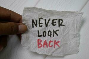 Never Look Back write on crunched paper isolated on wooden table. photo