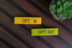 Opt In and Opt Out write on sticky notes isolated on Wooden Table. photo