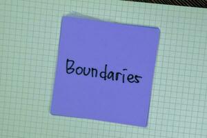 Concept of Boundaries write on sticky notes isolated on Wooden Table. photo