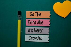 Go The Extra Mile It's Never Crowded write on sticky note isolated on Office Desk photo