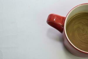 cerca arriba caliente capuchino café en un rojo taza aislado en un blanco antecedentes foto