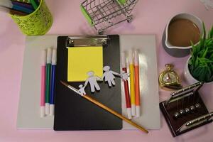 Top view of the cutting paper illustration a family on a pink table, preparing to do homework in a clipboard. Drawing Working Desk Concept photo