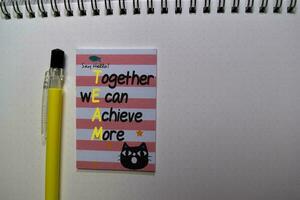 TEAM - Together wE can Achieve More write on sticky note isolated on Office Desk photo