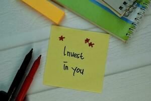 Invest in You write on sticky note isolated on Wooden Table. Selective focus on Invest in You text photo