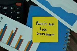 Profit and Lost Statement write on sticky notes isolated on Wooden Table. Business or Finance concept photo