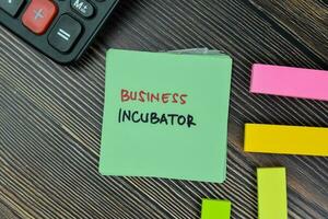 Business Incubator write on sticky notes isolated on Wooden Table. photo