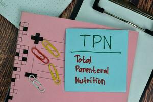 TPN - Total Parental Nutrition write on sticky notes isolated on Wooden Table. photo