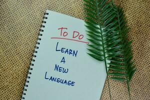 To Do - Learn A New Language write on a book isolated on Wooden Table. photo