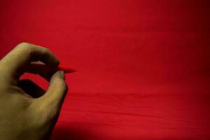 Man hand with red pen writing on red background photo